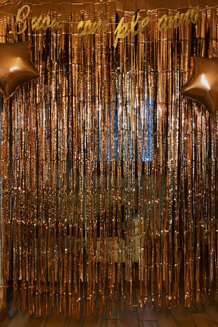 gold foil streamers hanging from the ceiling in front of a wall with two lights