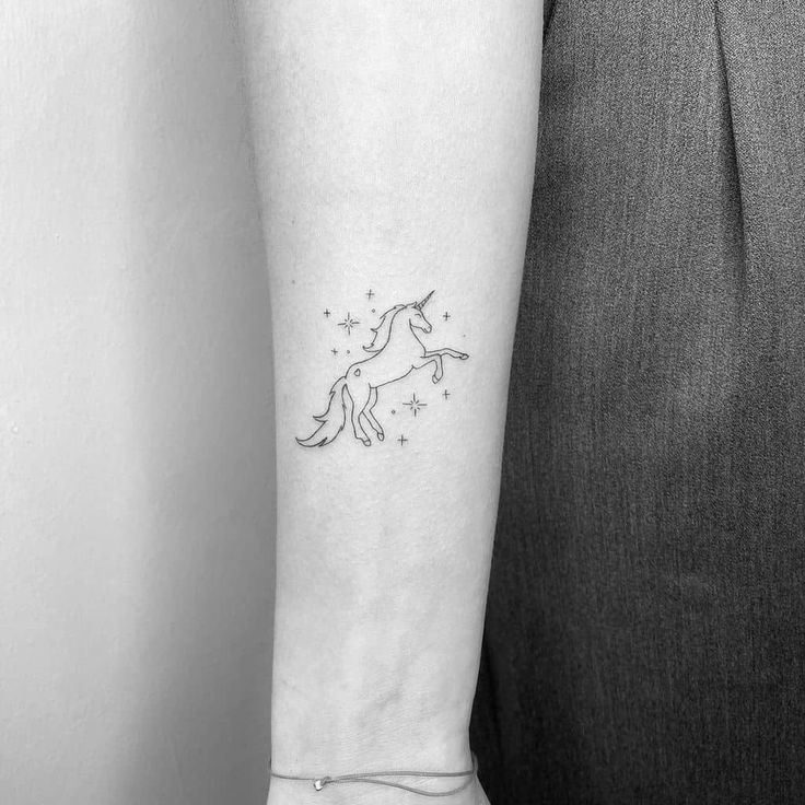 a woman's arm with a unicorn tattoo on it