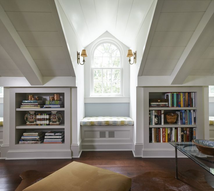 a living room filled with lots of furniture and bookshelves next to a window