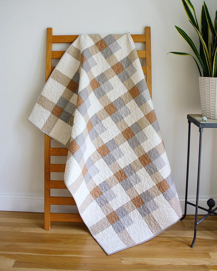 a chair with a blanket on it next to a potted plant