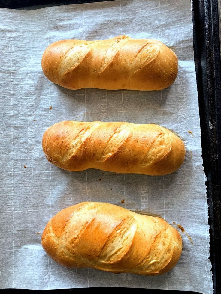 three loaves of bread sitting on top of a piece of parchment paper next to each other