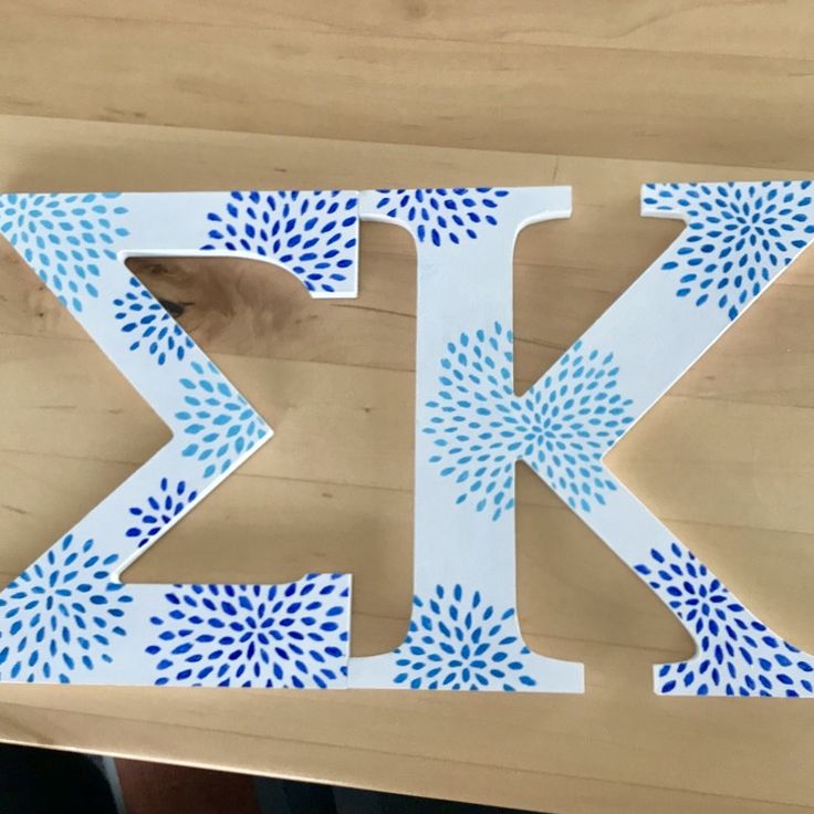 the letter k is made out of paper and has blue sprinkles on it