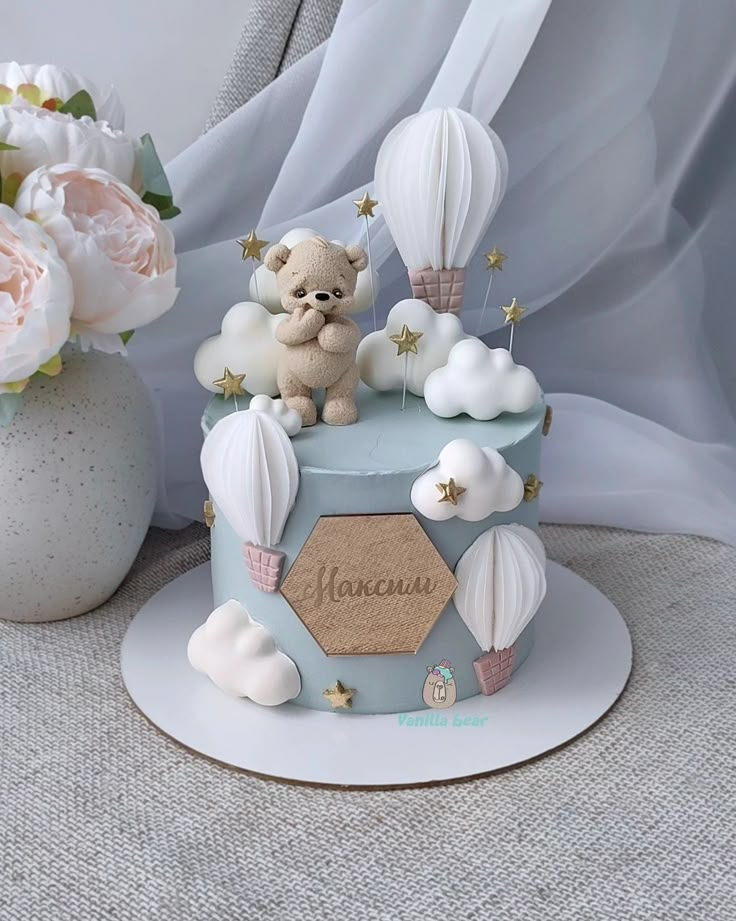 there is a small cake decorated with hot air balloons and a teddy bear on top