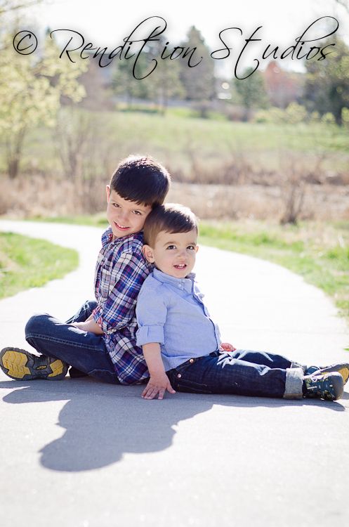 two young boys sitting on the ground with their arms around each other