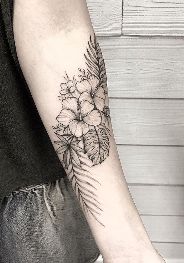 a black and white flower tattoo on the left arm, with palm leaves around it