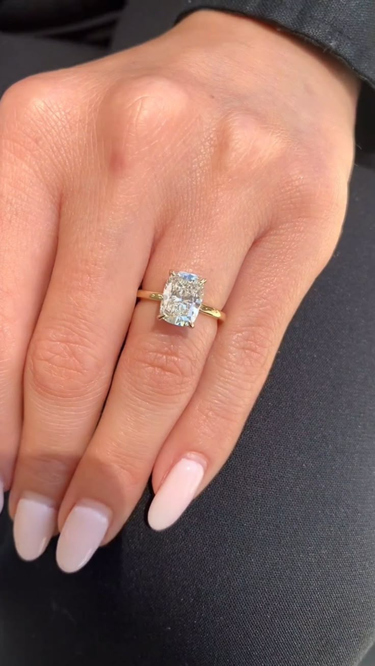 a woman's hand with a ring on her finger and an oval shaped diamond in the middle