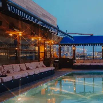 an indoor swimming pool with lounge chairs and tables next to it in front of a building