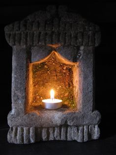 a candle is lit in a stone shrine