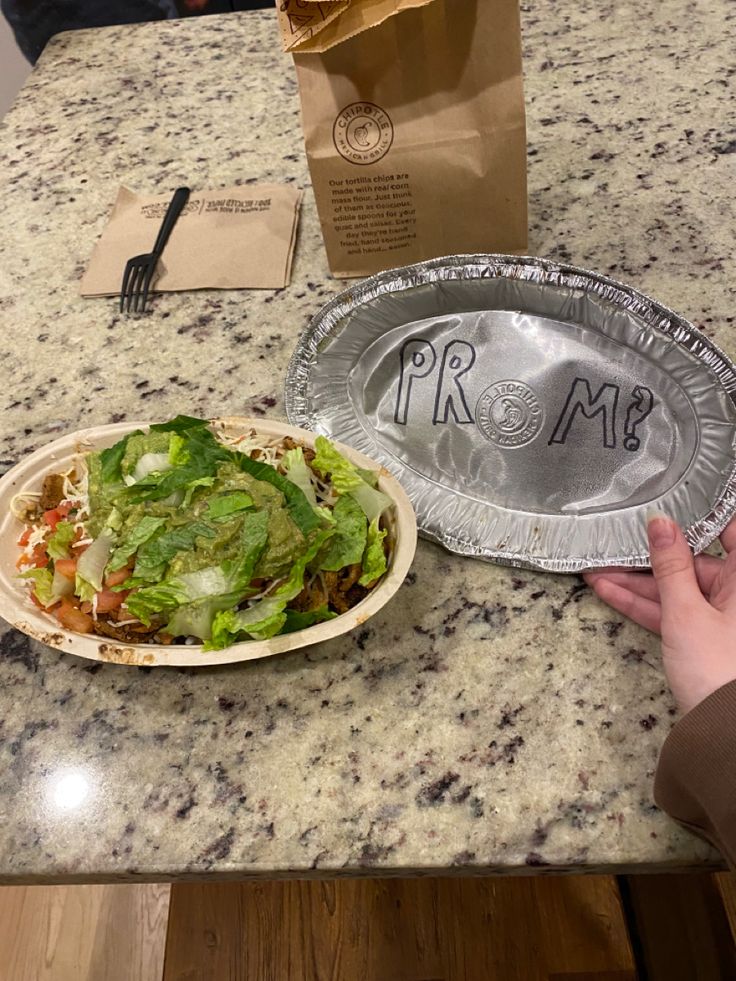 a person is sitting at a table with a plate of salad