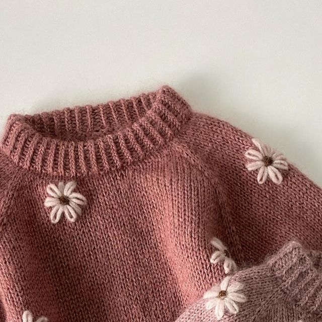 a pink sweater with white flowers on it