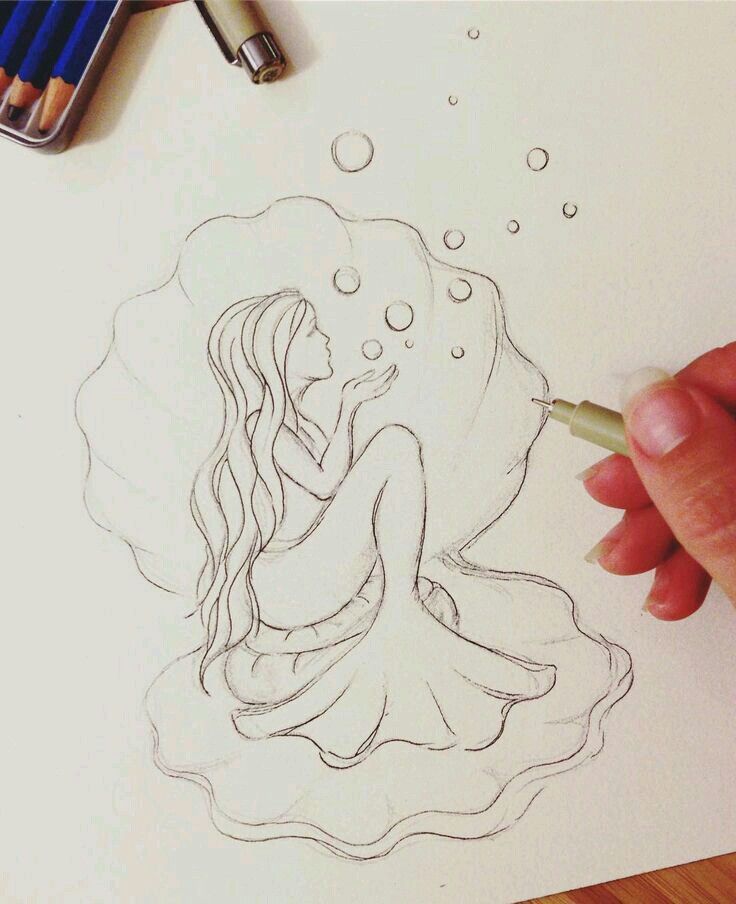 a drawing of a mermaid sitting on top of a sheet of paper with pencils next to it