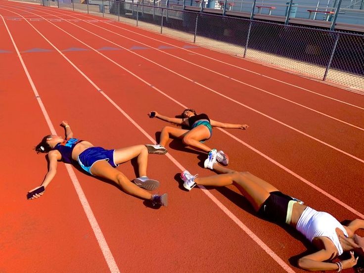 two women are laying on the running track