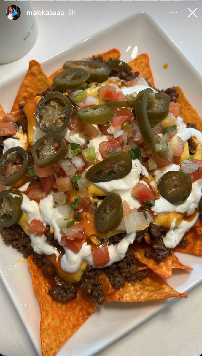 nachos on a plate with sour cream, cheese and toppings in the middle