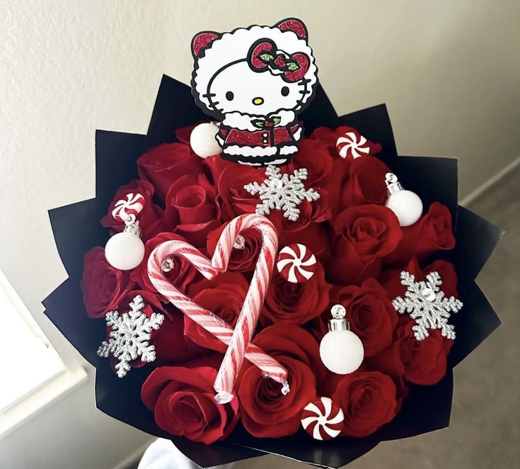 a bouquet of red roses and candy canes in the shape of a hello kitty