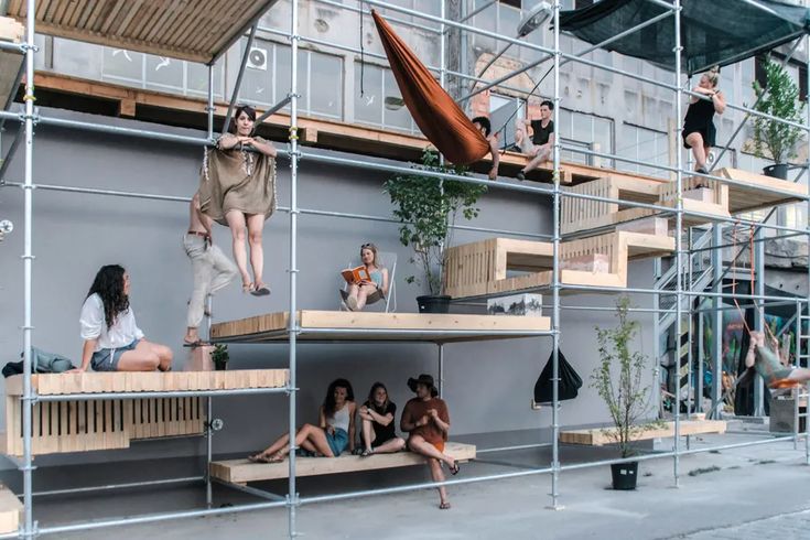 several people hanging out on scaffolding in front of a building