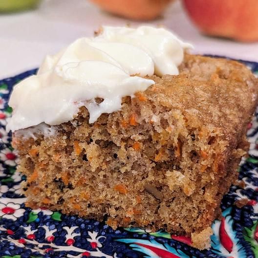 a piece of carrot cake with white frosting on a blue and multicolored plate