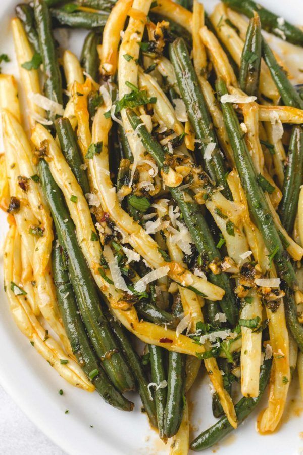 green beans with parmesan cheese and herbs in a white bowl on a table