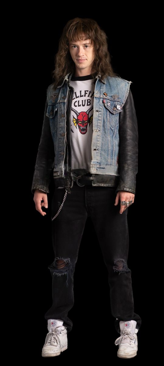 a young man with long hair wearing a jean jacket and white shirt standing in front of a black background