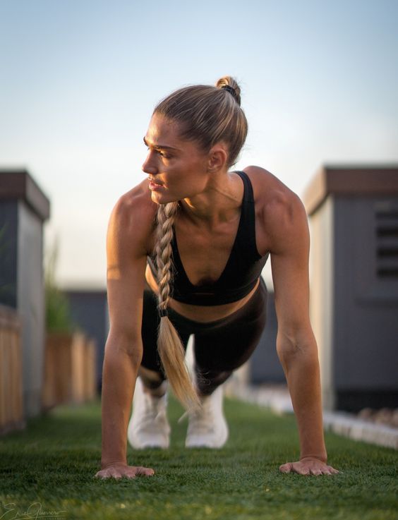 a woman doing push ups in the grass