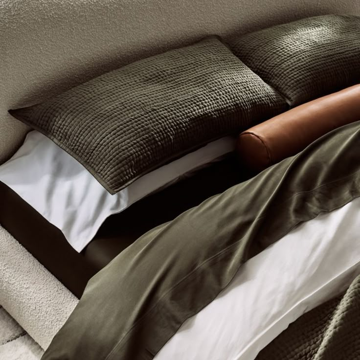 a bed with two pillows on top of it next to a blanket and pillow case