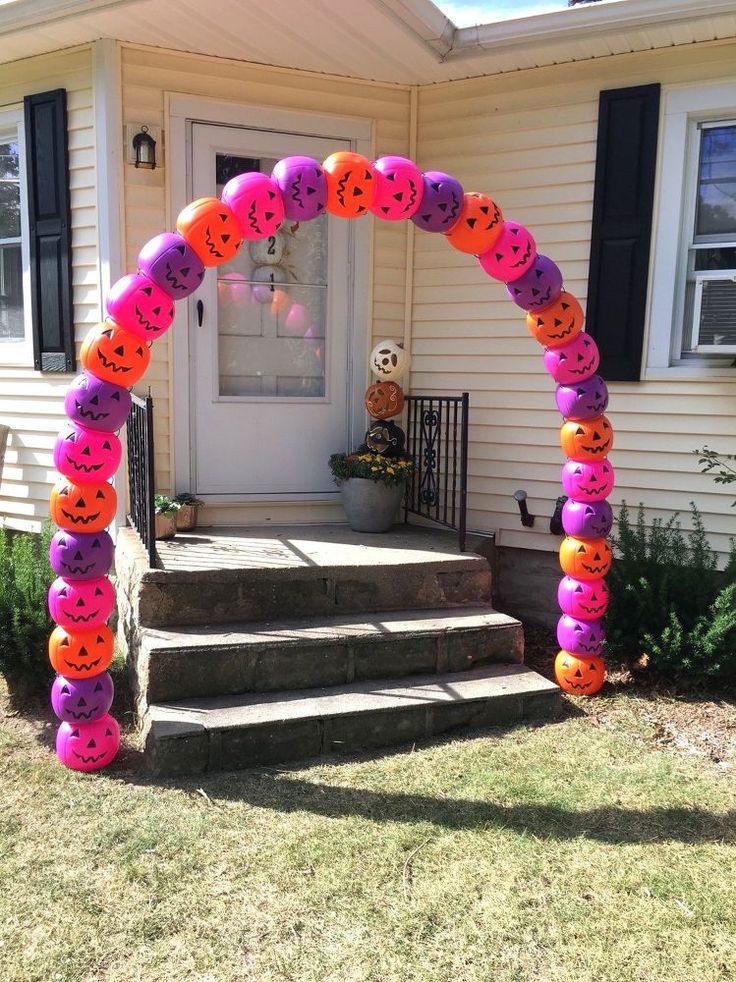 an arch made out of balloons with pumpkin faces on it in front of a house