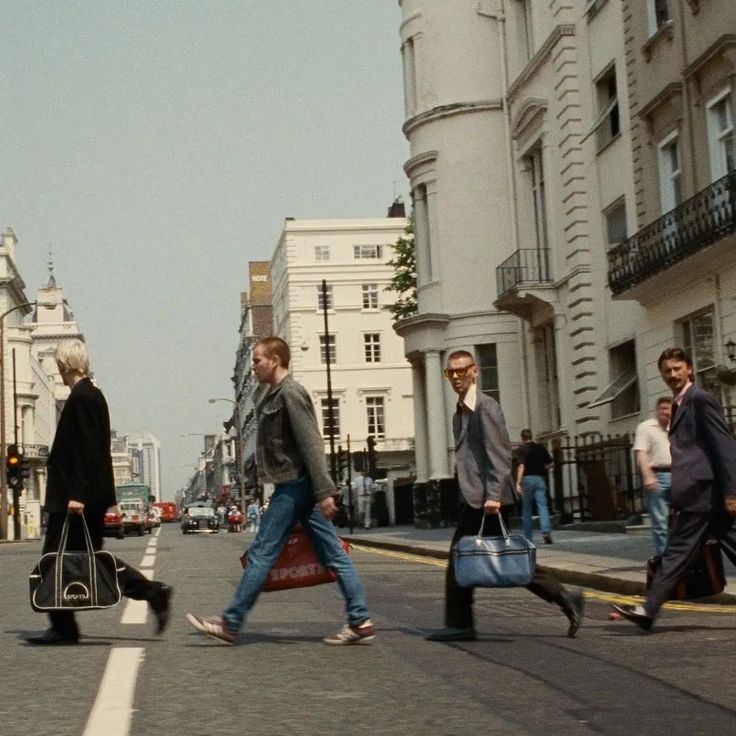 several people walking across the street with their suitcases in hand and one person carrying a bag