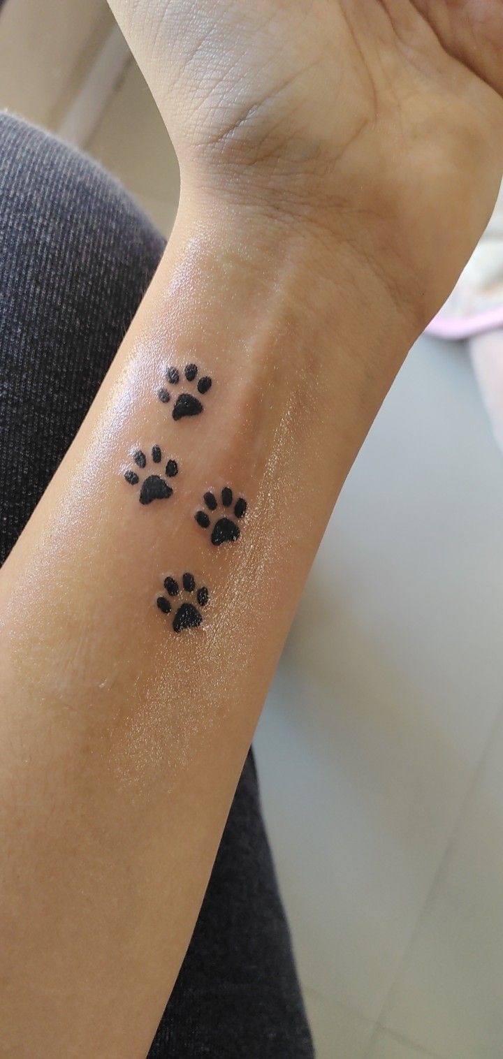 a woman's wrist with small black dog paw prints on the left side of her arm