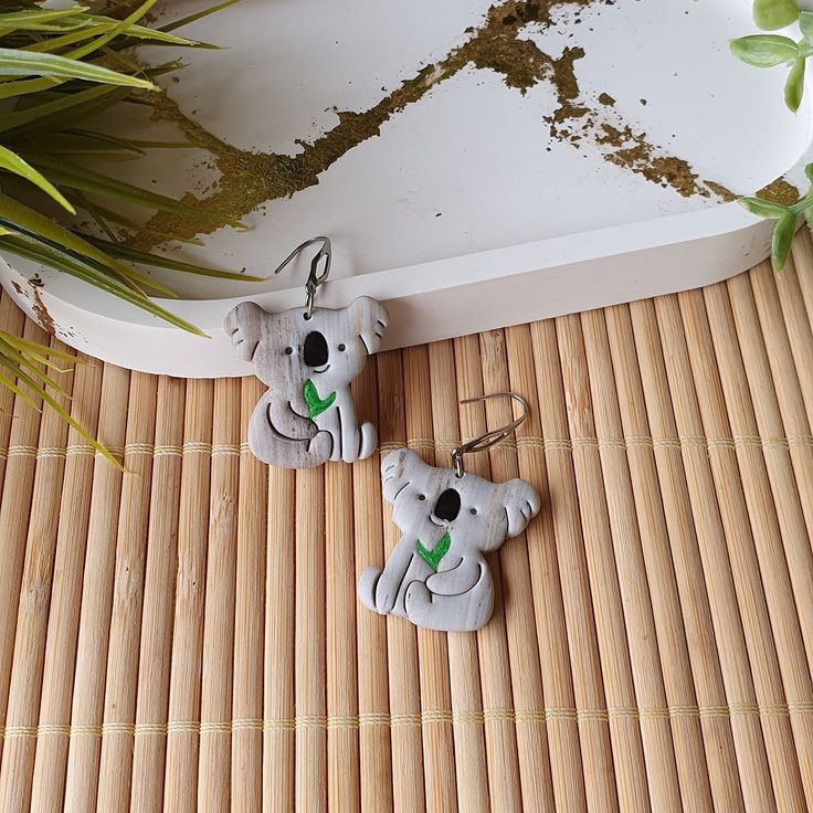 two koalas are sitting on the floor next to a potted plant and bamboo mat