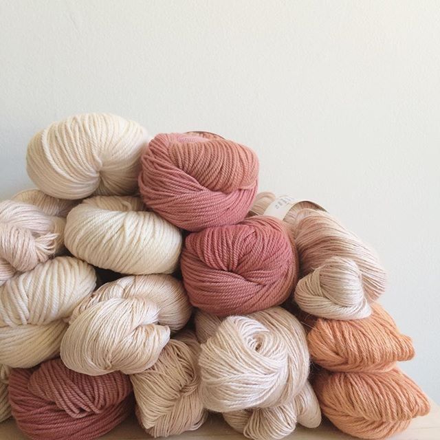 a pile of yarn sitting on top of a wooden table next to a white wall