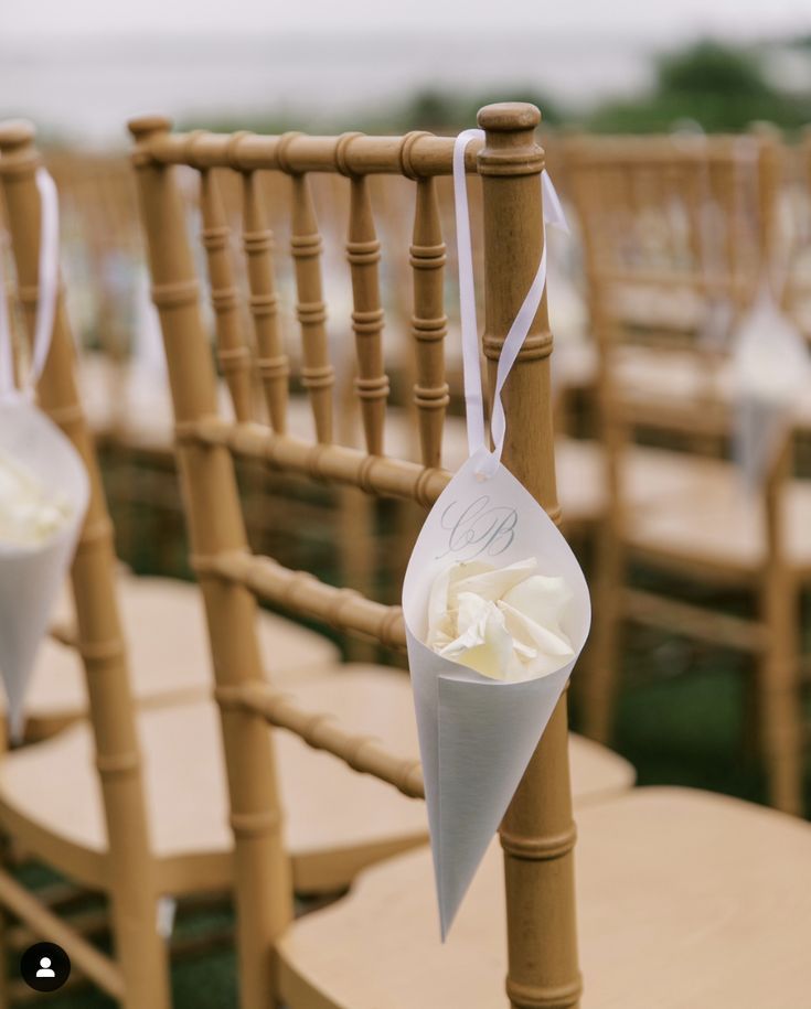 an arrangement of chairs with white flowers tied to the back and one flower in a cone