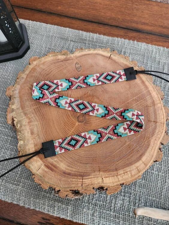 two colorful beaded bracelets sitting on top of a piece of wood next to an electronic device