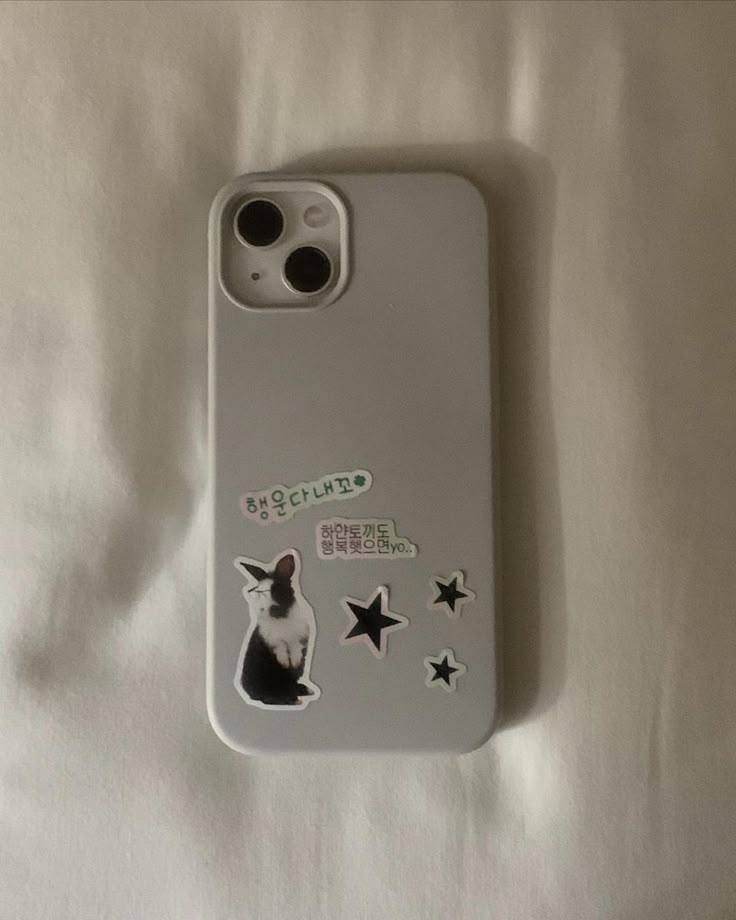 a cell phone case with a cat sticker on the front and star decals on the back