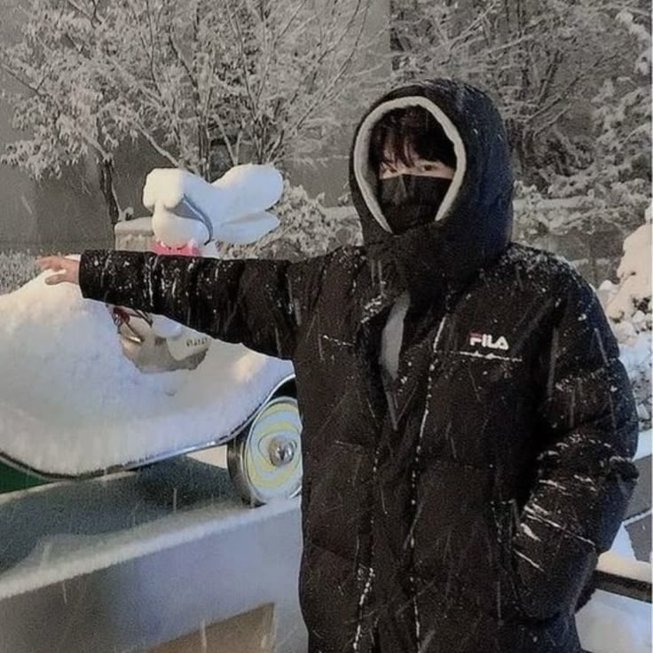 a man standing next to a snowboard on top of a wooden table covered in snow