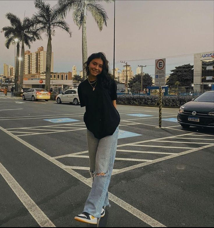 a woman standing in the middle of a street with palm trees and buildings behind her