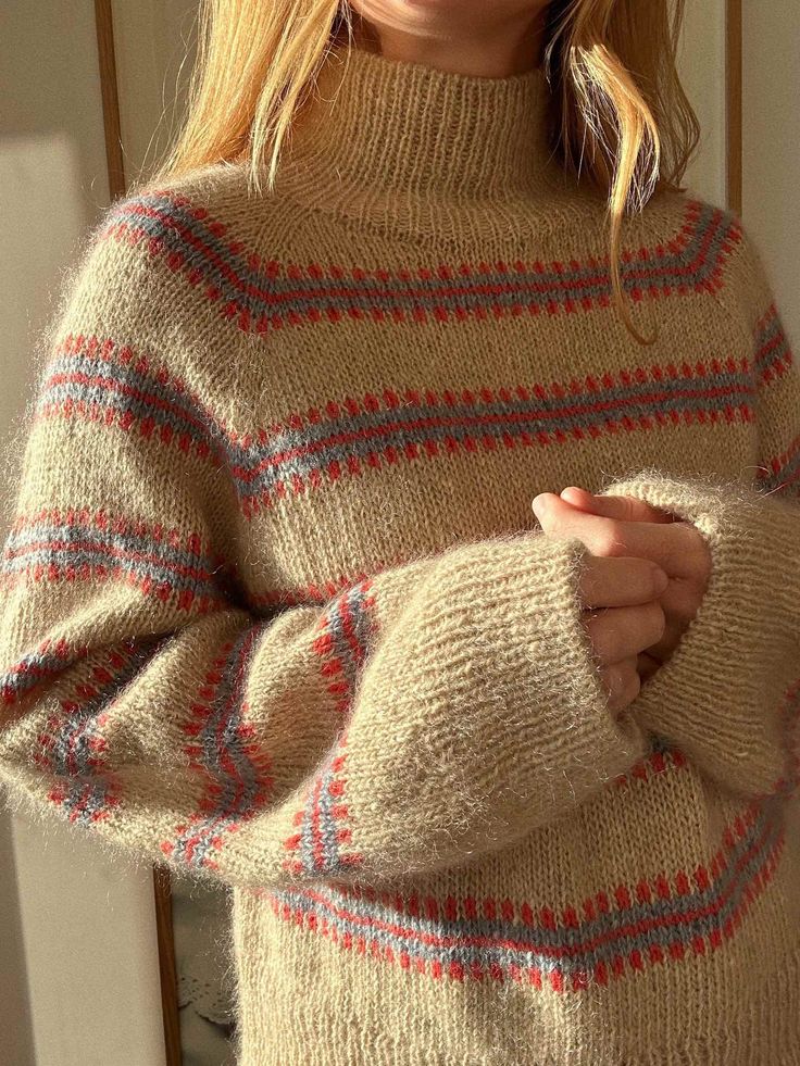 a woman is wearing a sweater and posing in front of a mirror with her hands folded