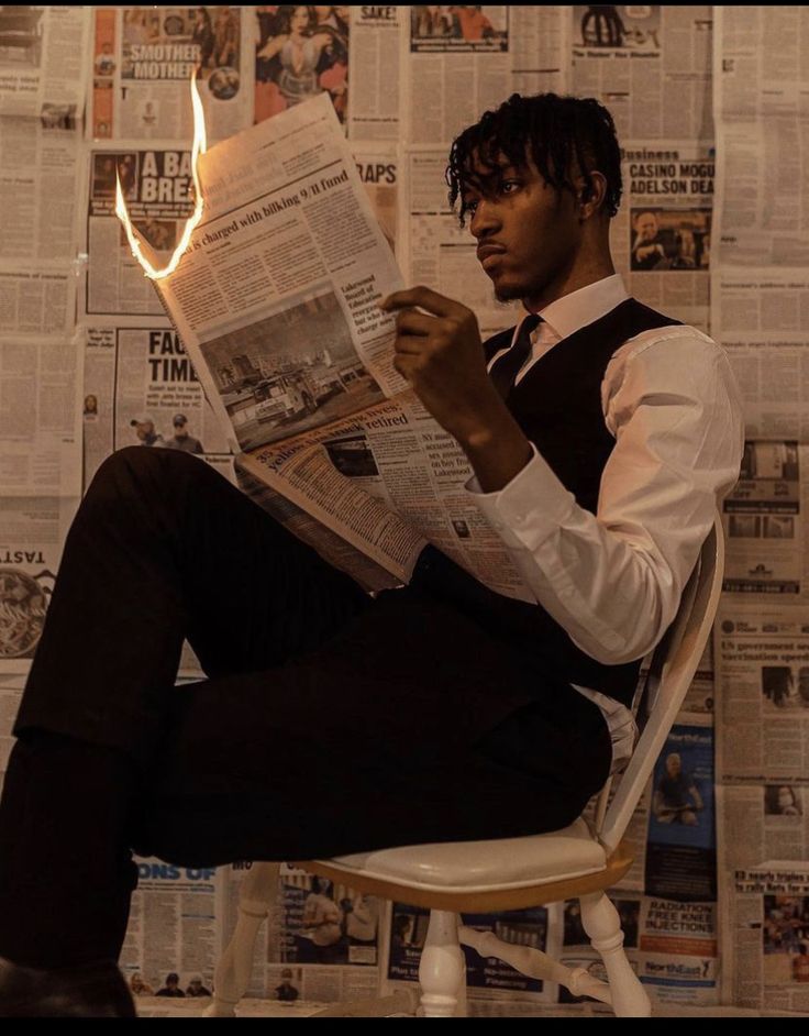 a man sitting in a chair reading a newspaper while holding a lit match with his right hand