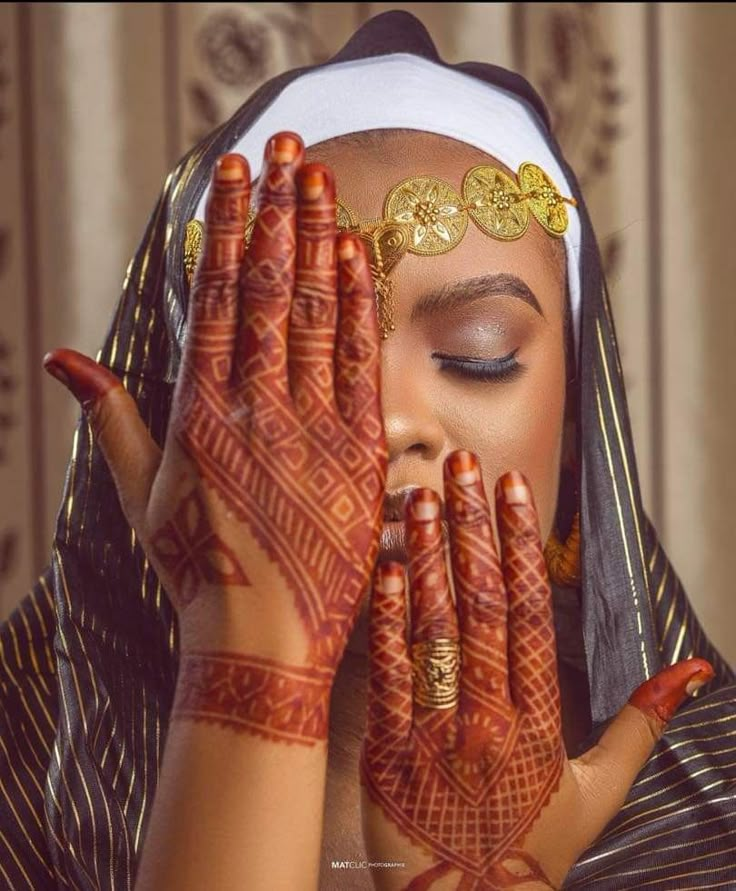 a woman with her hands on her face and painted in hendi, is looking at the camera