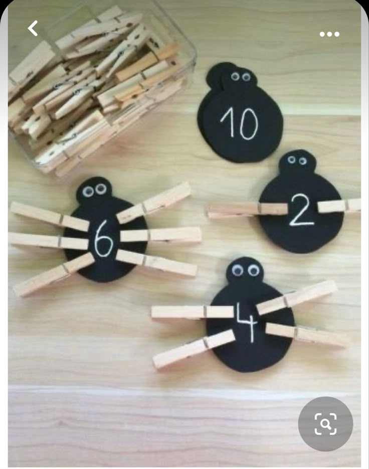 wooden pegs with faces and numbers on them sitting next to a container of clothes pins