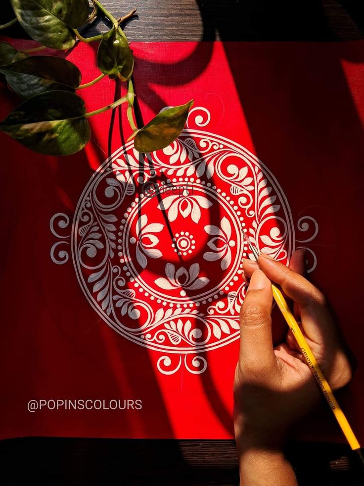 a person holding a pencil and drawing on a piece of paper with a red background