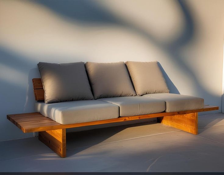 a couch sitting on top of a wooden bench next to a wall with white walls