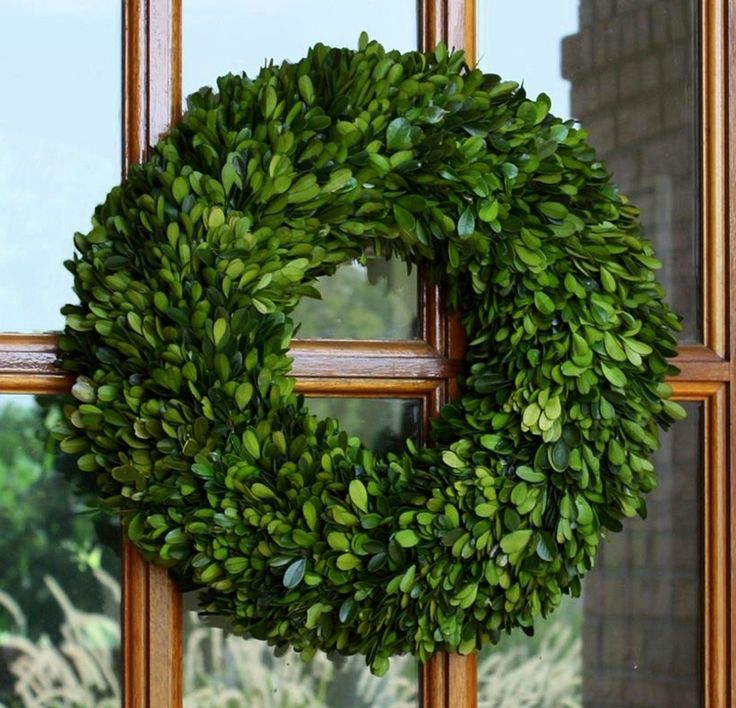 a green wreath hanging on the side of a window