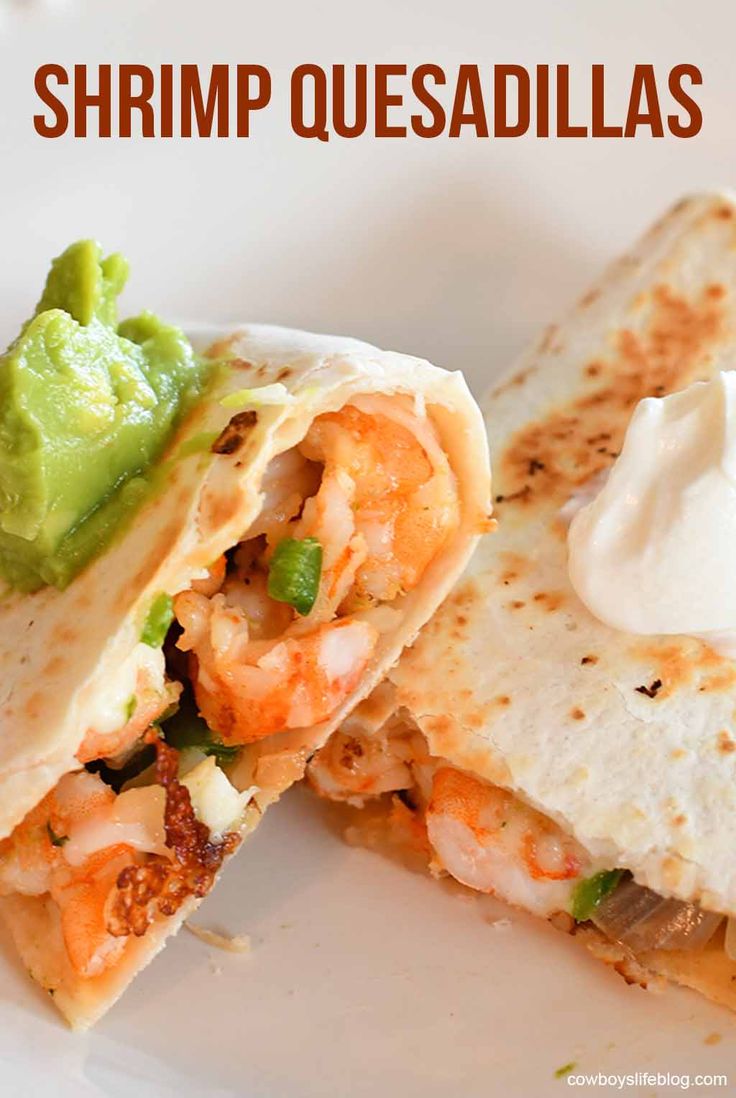 a close up of a burrito on a plate with sour cream and guacamole