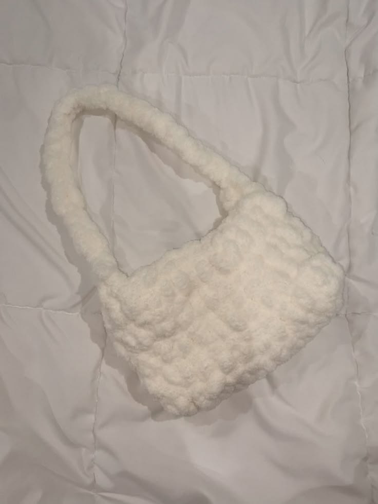 a white purse laying on top of a bed