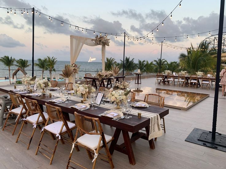 an outdoor dining area with tables and chairs set up on the deck overlooking the ocean