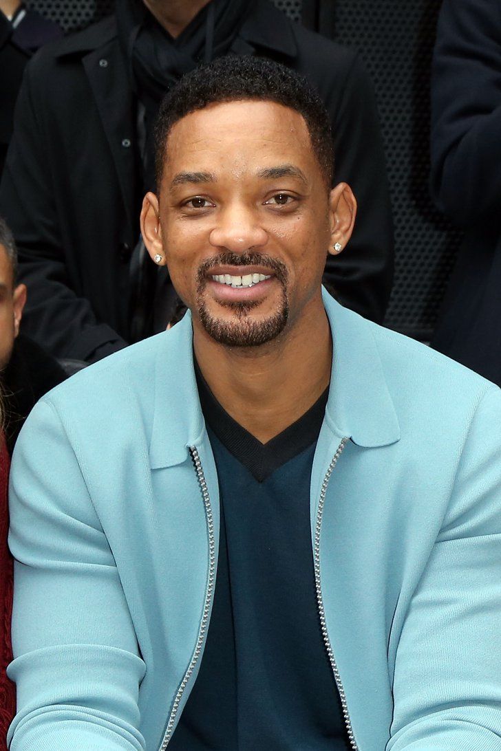 a man sitting in front of a crowd wearing a blue jacket and black t - shirt