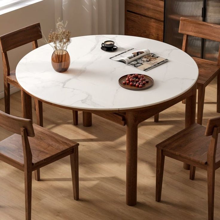 a white table with wooden chairs around it and a bowl of fruit on the table