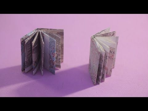 an open book sitting on top of a purple table next to another folded up book