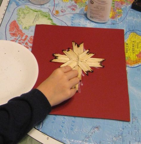 a child is making a paper snowflake ornament on a red card