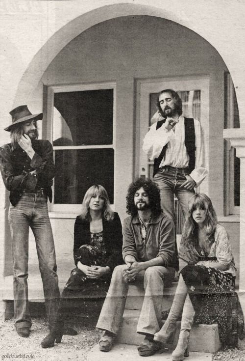 an old black and white photo of people sitting on the front steps of a house