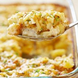 a spoon full of macaroni and cheese being lifted from a casserole dish